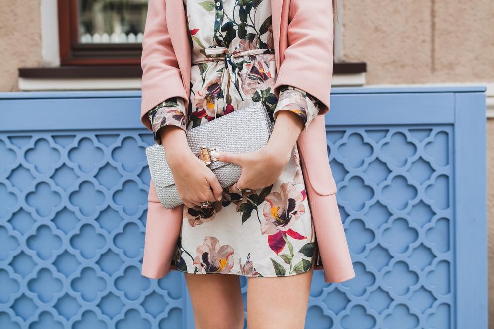woman in a floral print drss and pink coat